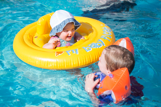A baby and a toddler swimming in a pool